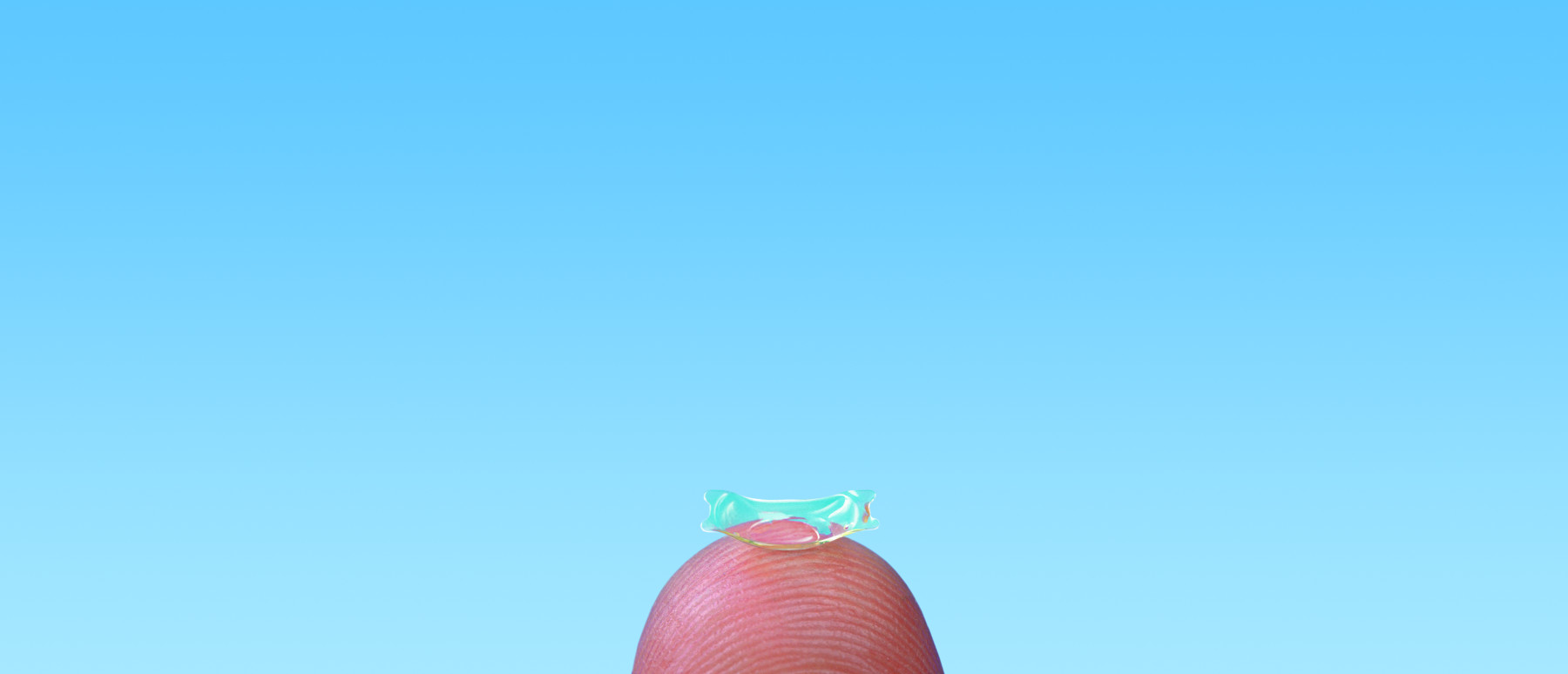 Bild zeigt eine implantierbare Kontaktlinse auf einer Fingerkuppe fotografiert