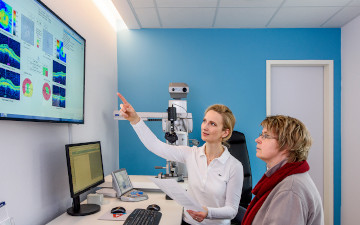 Beratungsgespräch von Augenärztin Dr. Sina Ahlers mit einer Patientin vor einem großen Bildschirm zum Thema AMD